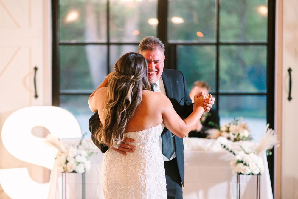 Wedding dance captured in romantic lighting with illuminated decor and floor-length windows.