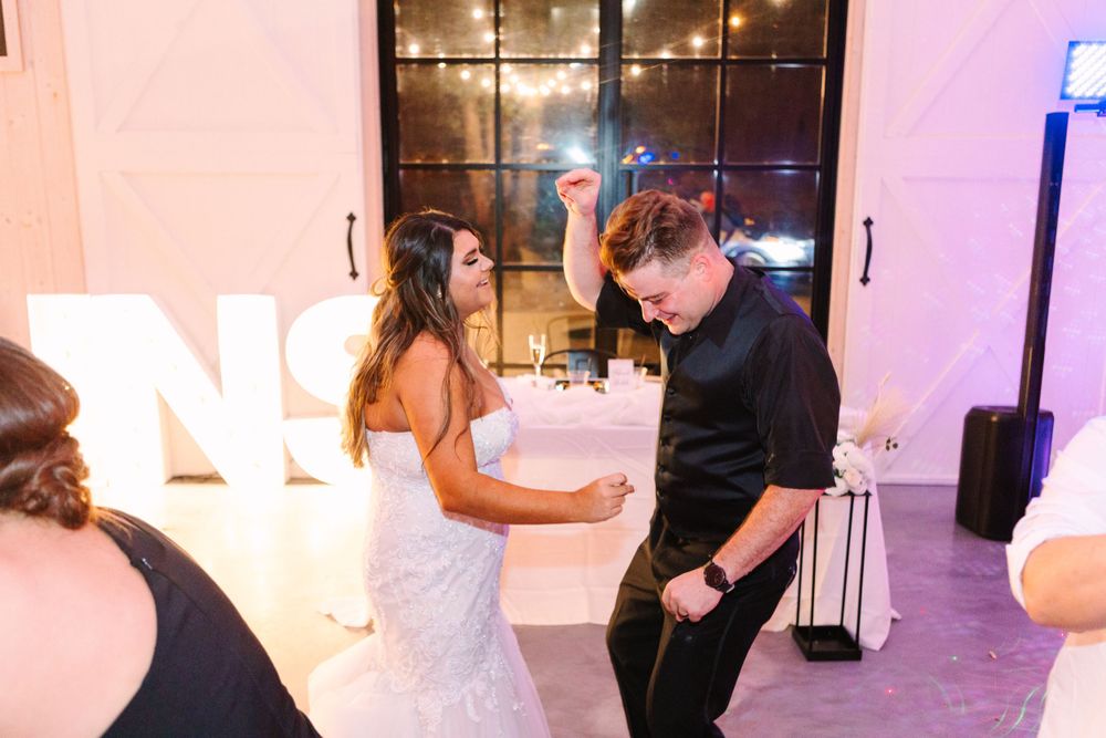 Couple dancing together near illuminated marquee letters at their wedding reception.