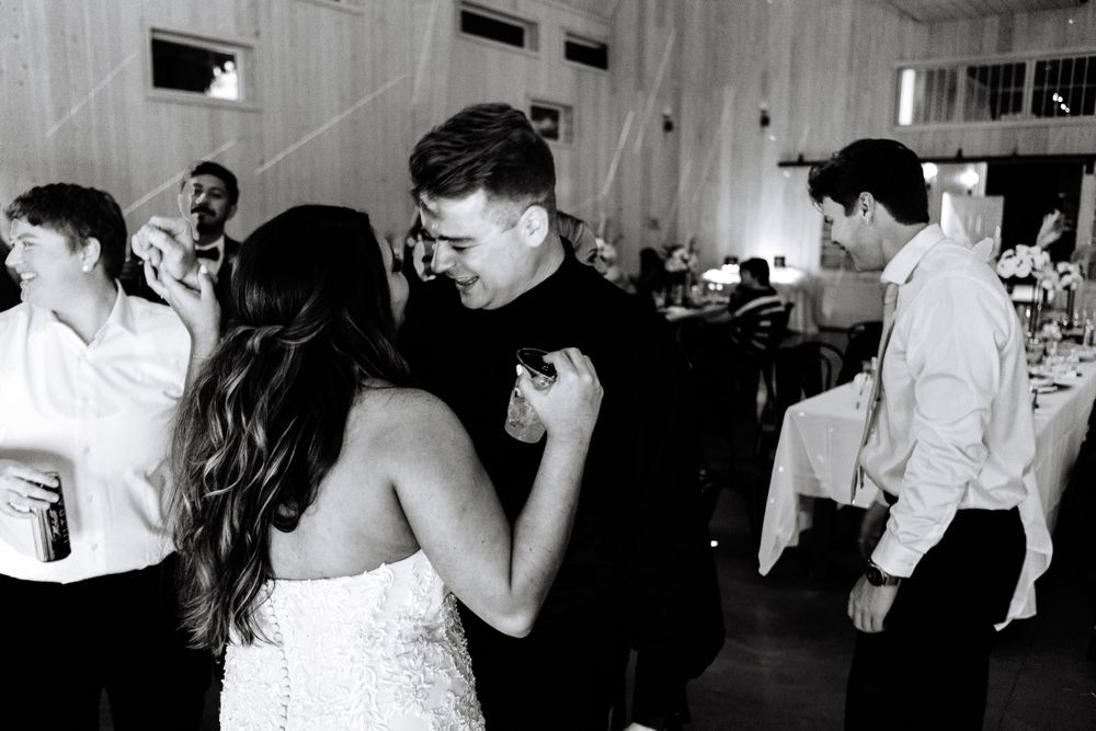 A couple shares a romantic slow dance moment at their wedding reception in black and white.