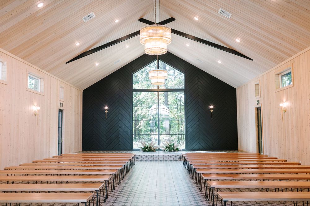 Modern chapel interior with wood beam ceiling and black accent wall featuring large windows.