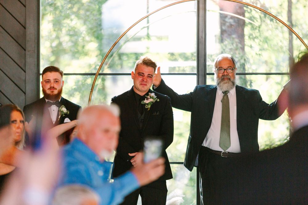 Wedding celebration with guests cheering in a modern venue with large windows.
