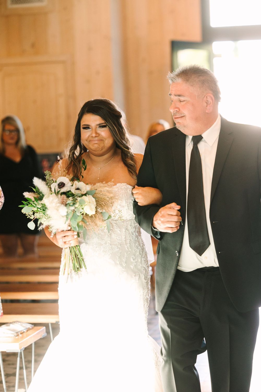 Walking down the aisle moment in a sunlit ceremony space.