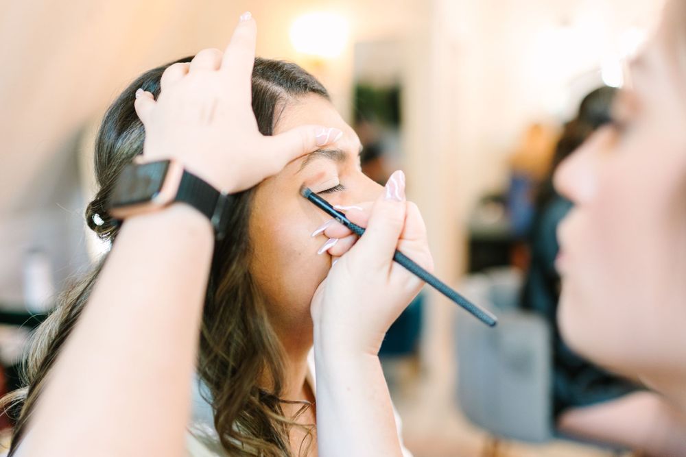 Close-up shot of makeup being applied with a brush during wedding preparations.