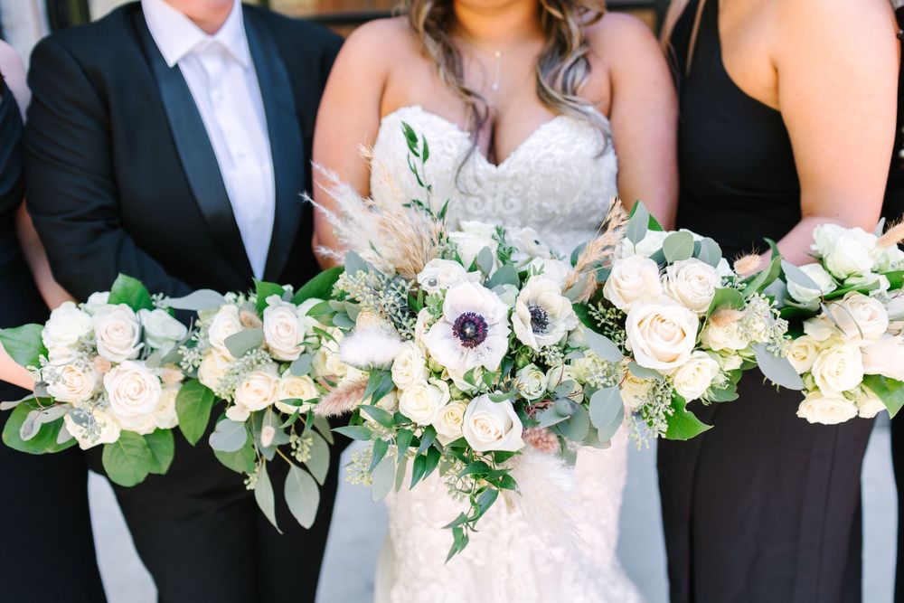 Elegant white and green wedding bouquets with anemones and eucalyptus leaves displayed against formal attire.