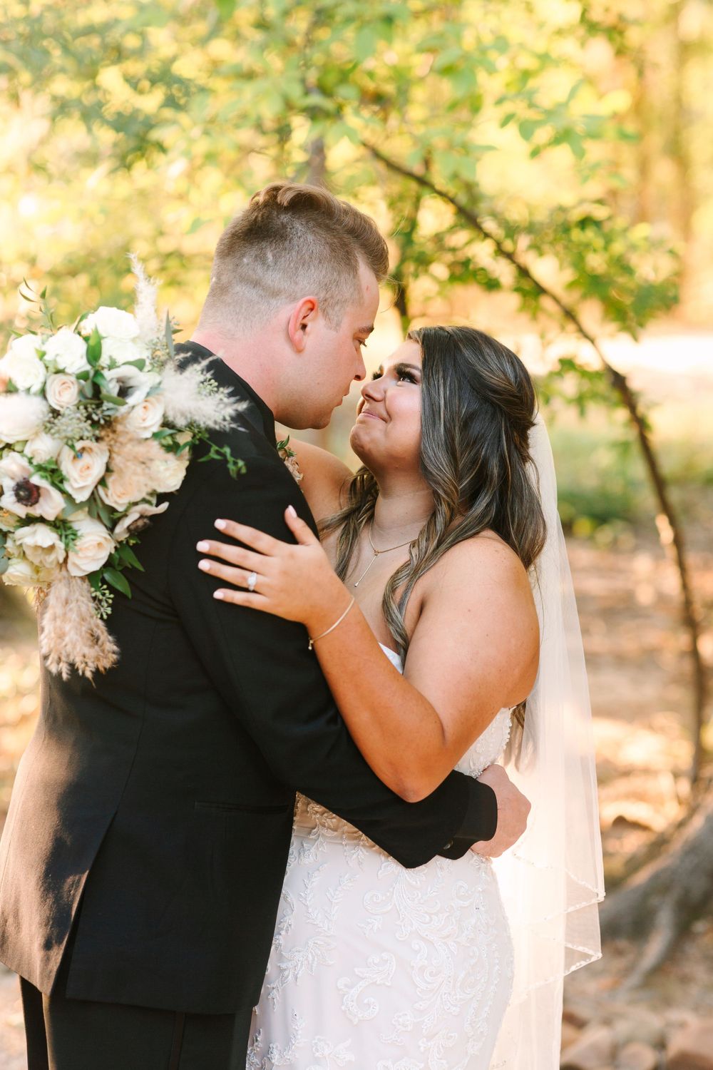 Romantic autumn wedding portrait with couple embracing among golden foliage.
