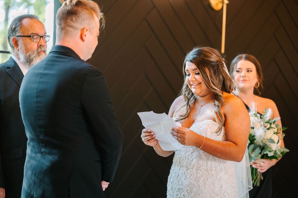 Couple exchanging vows during wedding ceremony while bride reads from paper.