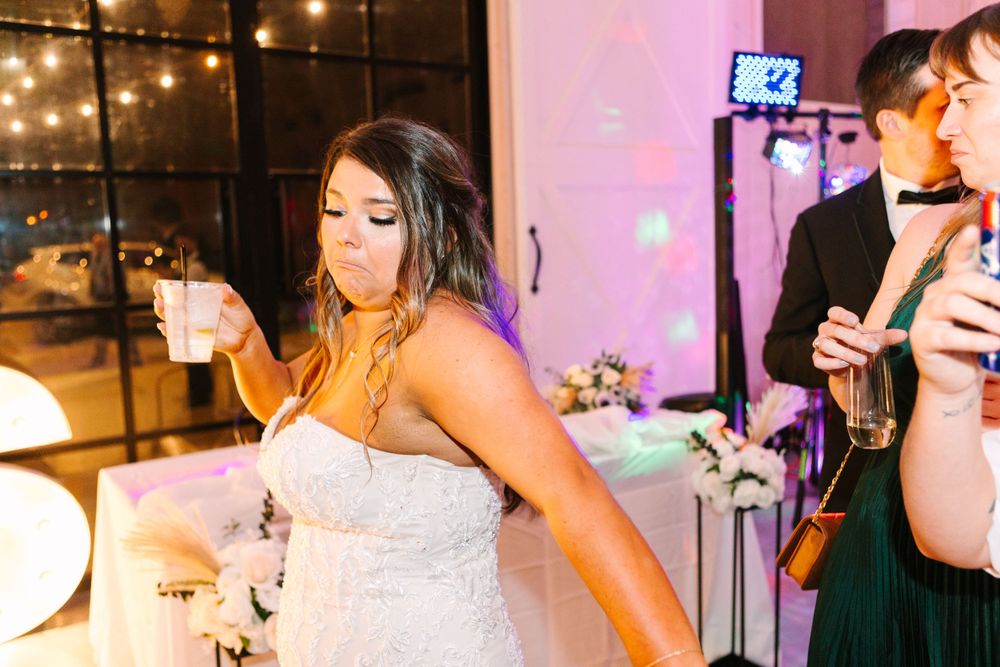 Wedding celebration with string lights and pink uplighting as dancing continues on the dance floor.