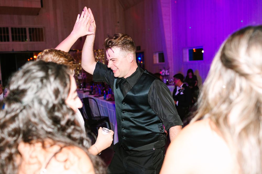Reception party with pink lighting as guests dance and celebrate.