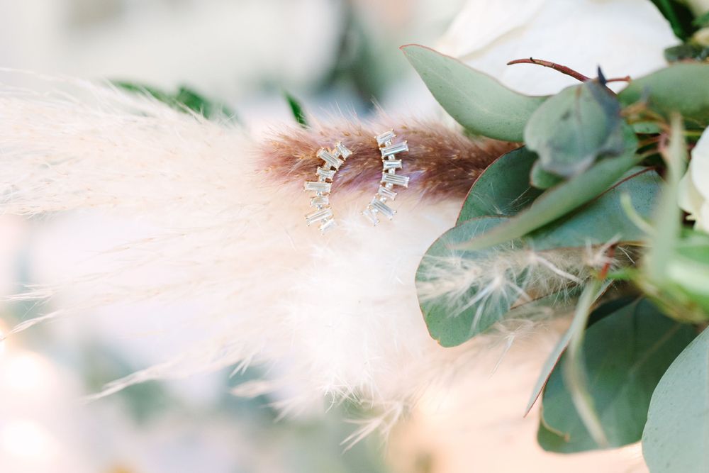 Delicate wedding jewelry details with eucalyptus leaves and soft feathers.