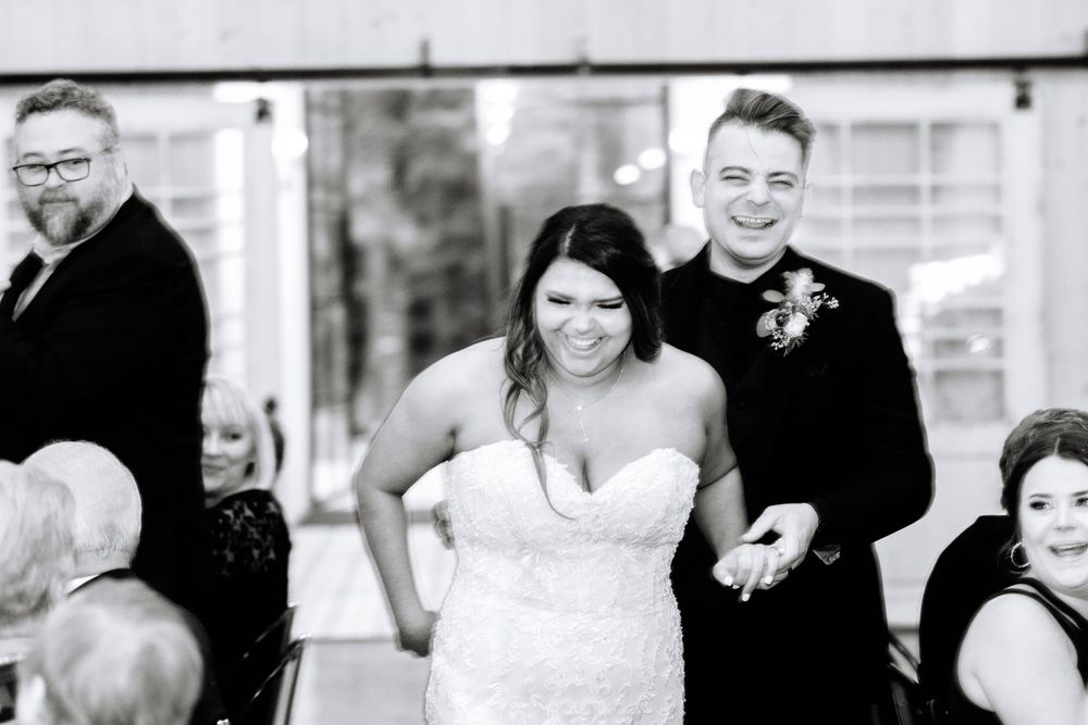Black and white photo of wedding party during ceremony in modern venue.