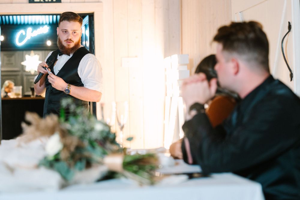 Reception dinner scene with staff member serving guests at elegantly decorated table.