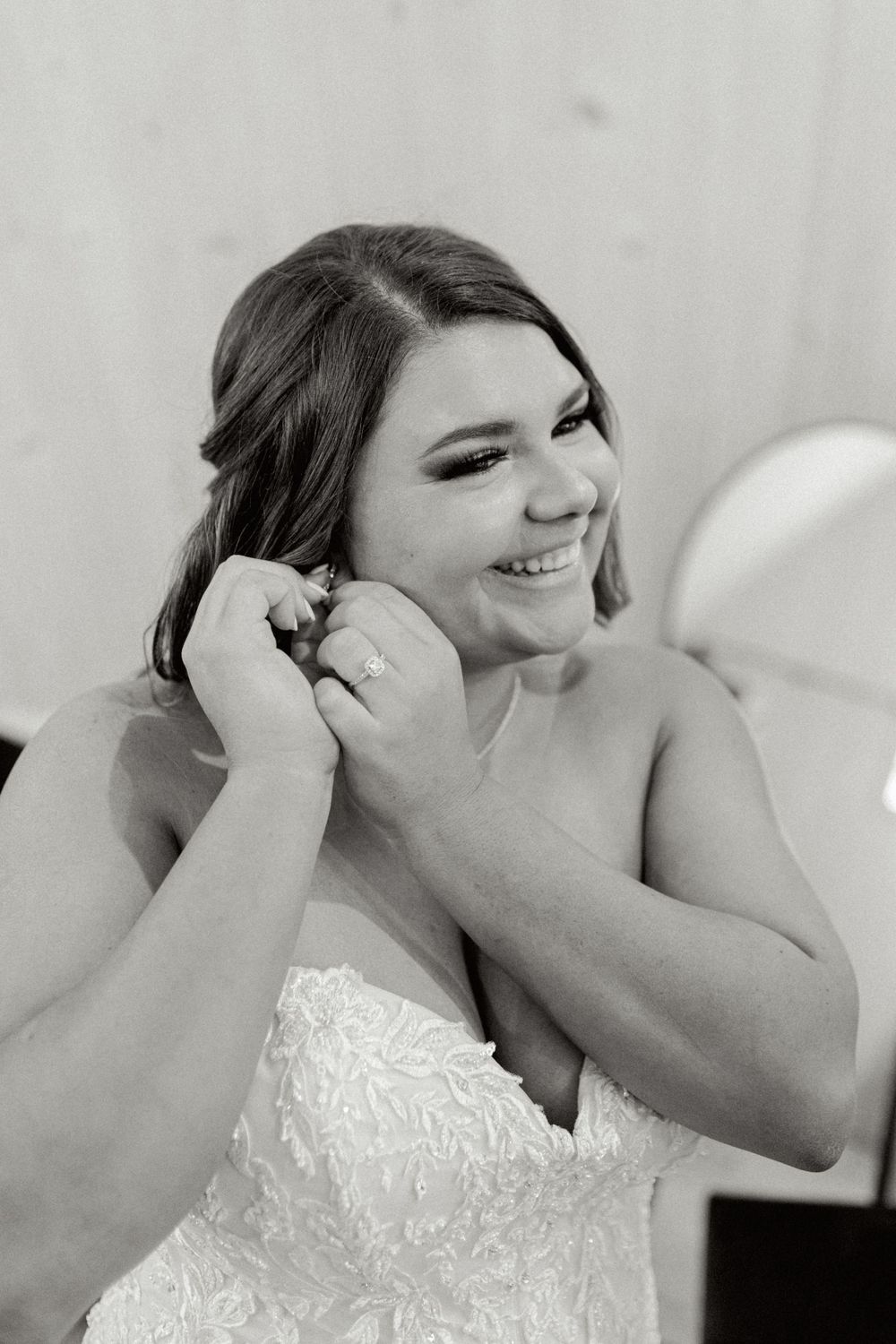 Black and white portrait of bride smiling while getting ready.