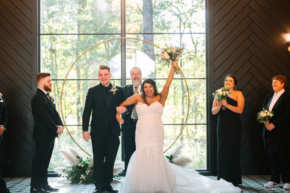 Celebratory moment during wedding ceremony with raised arms in modern chapel setting.