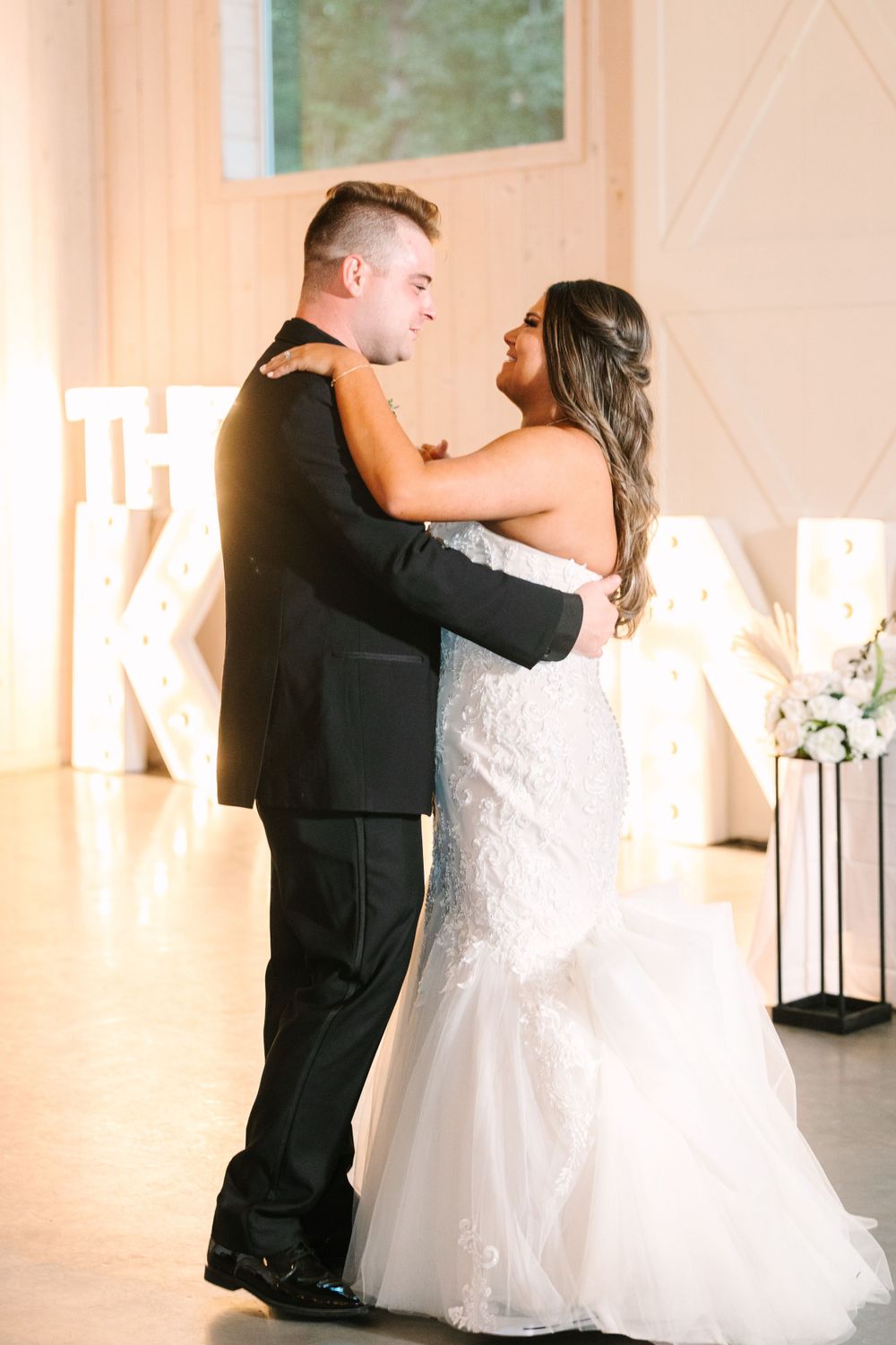 Couple sharing intimate dance moment in white reception venue.