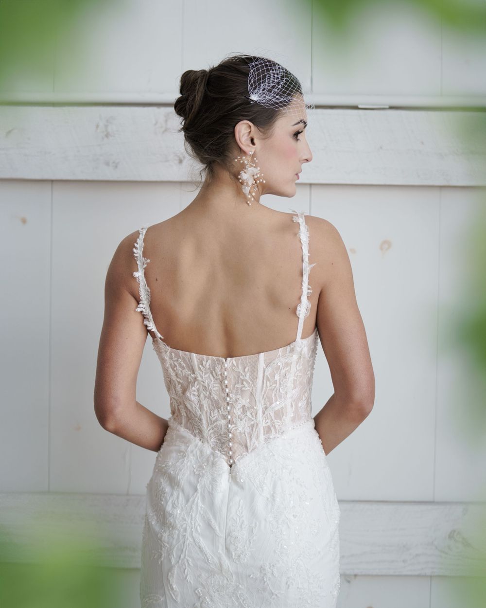 Detailed back view of an elegant white lace wedding dress with delicate straps and sheer details.