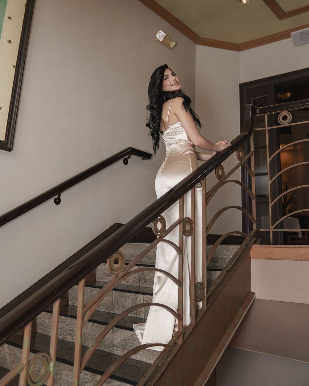 A sequence shows someone posing gracefully along an indoor staircase with wood and metal railings.