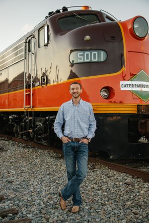 Person poses in front of vintage orange locomotive train number 5001.