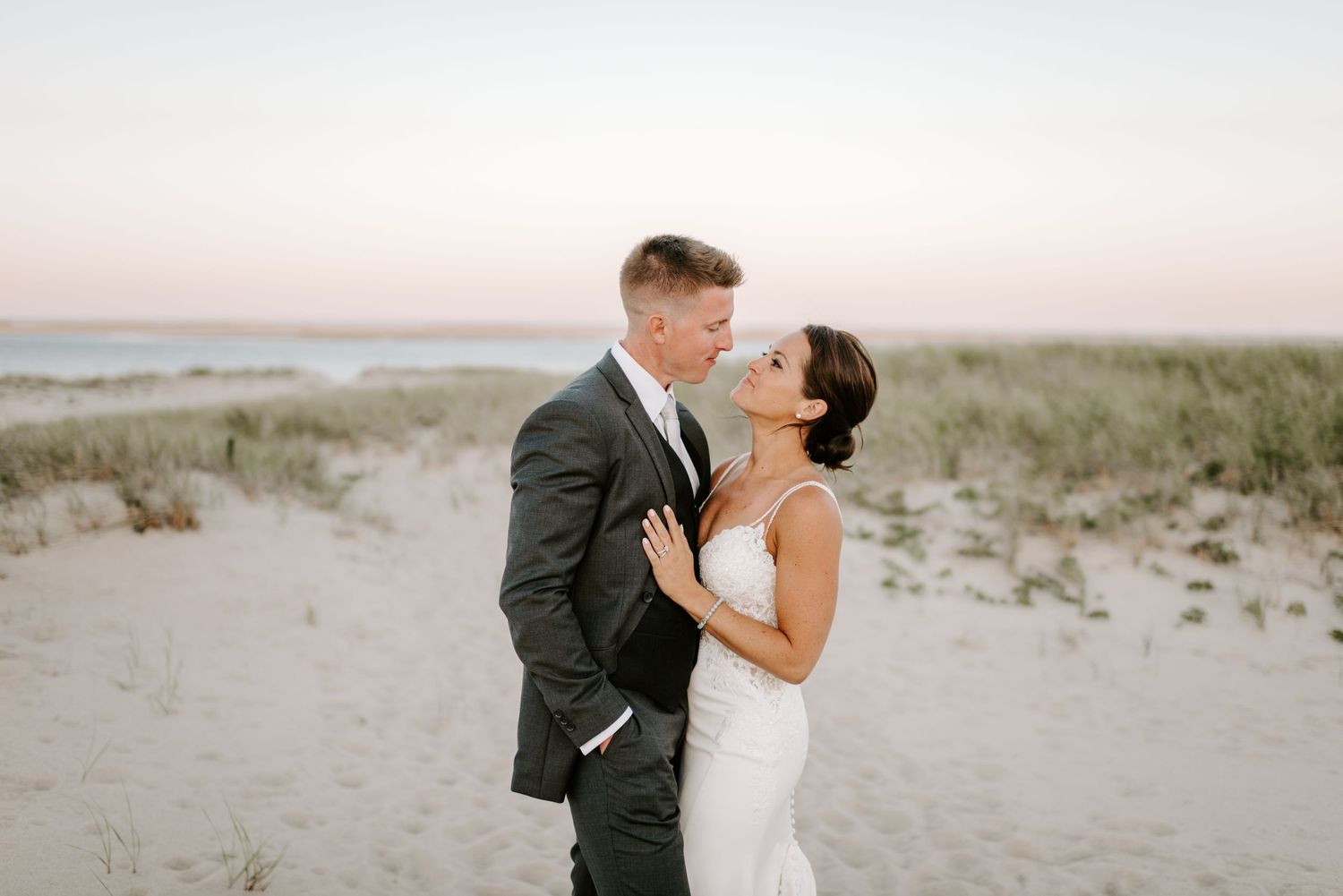 Romantic beach wedding photography session during sunset with coastal dunes.