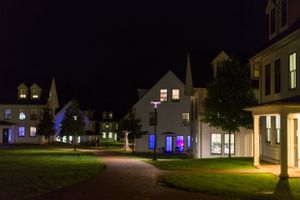 Historic buildings with illuminated windows and blue lights create a peaceful nighttime street scene.