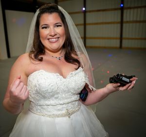 A person in a strapless white wedding dress poses in an indoor venue.