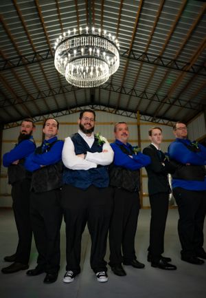 Groomsmen pose under a crystal chandelier in formal attire with blue accents.