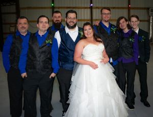 Wedding party poses together in coordinated blue and black attire.