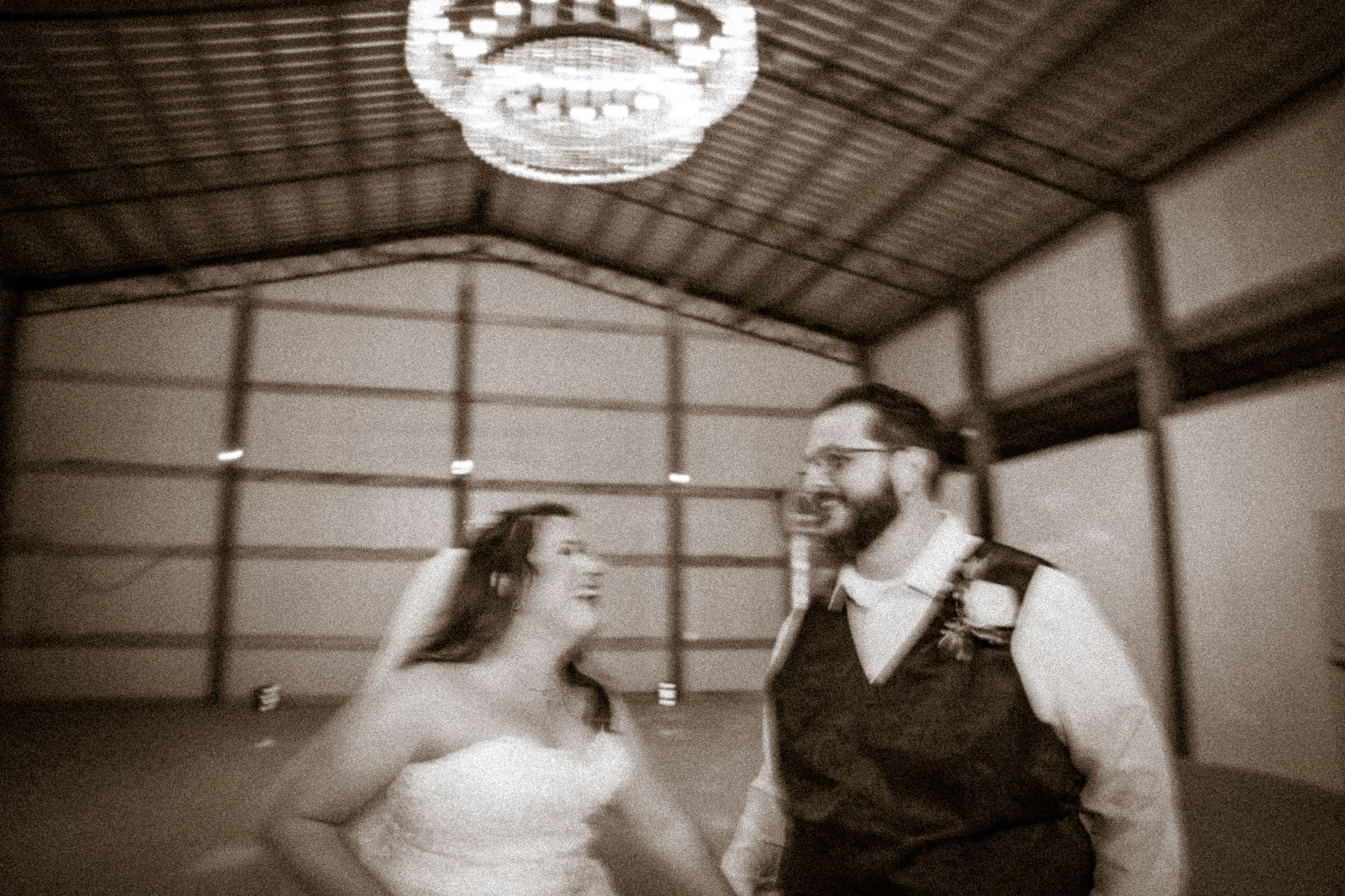 A sepia-toned candid moment between a couple during their wedding celebration.