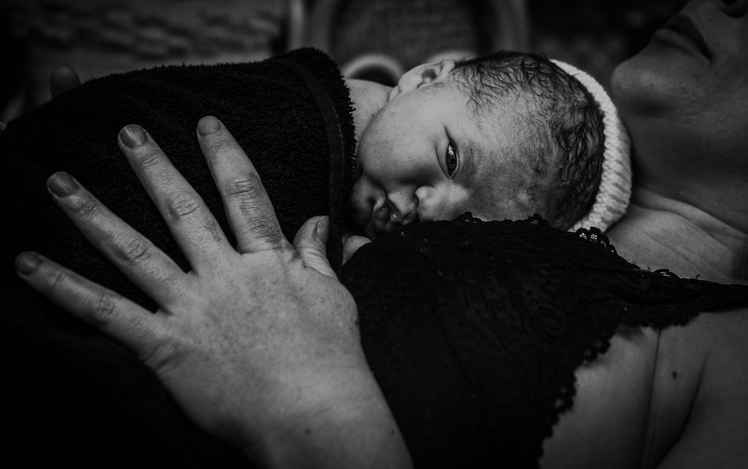 Intimate black and white close-up of newborn being held.