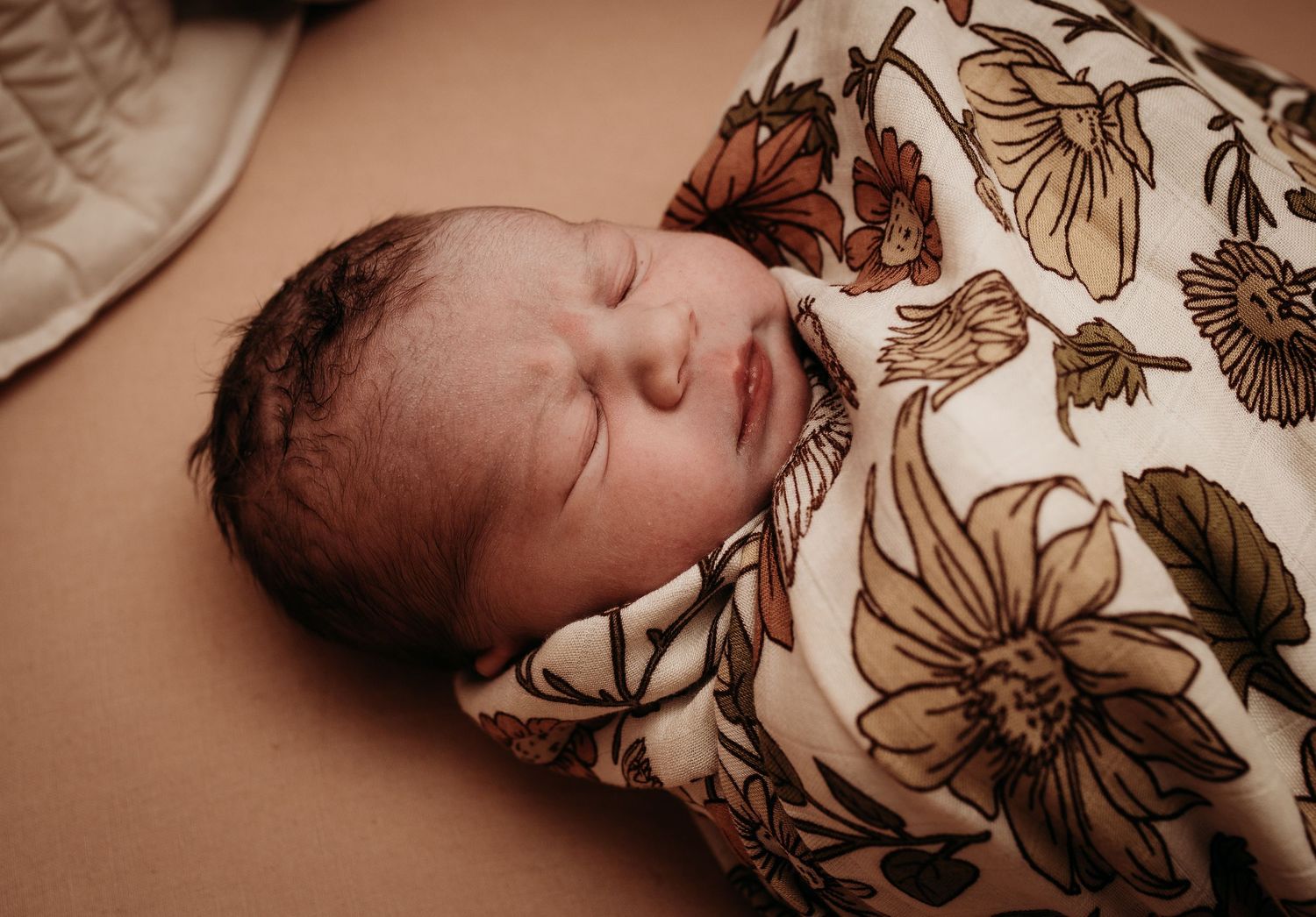 Artistic portrait of a sleeping newborn with floral pattern overlay.
