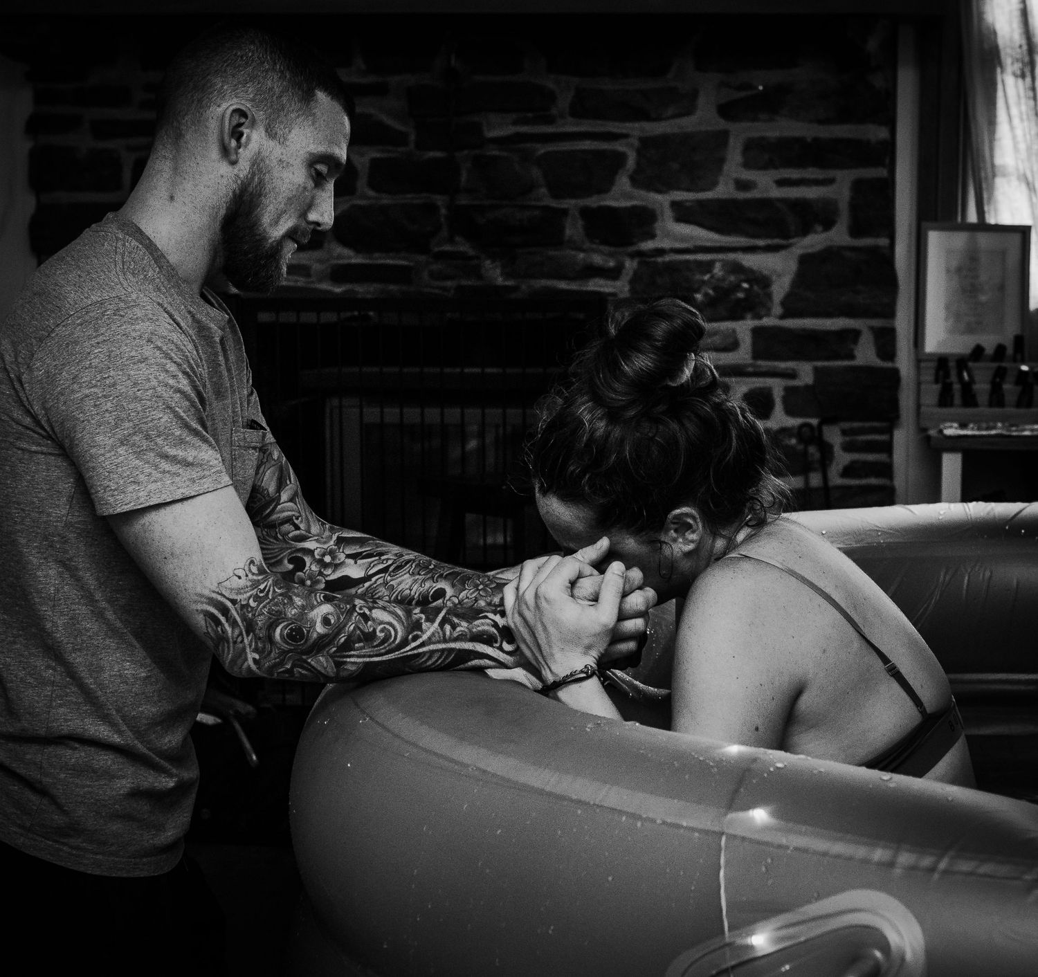 Support person providing comfort during labor in dimly lit room.