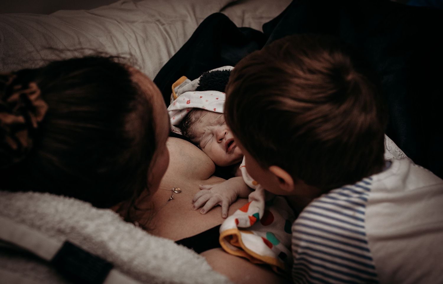 Intimate black and white photo series showing tender moments of skin-to-skin contact and bonding.