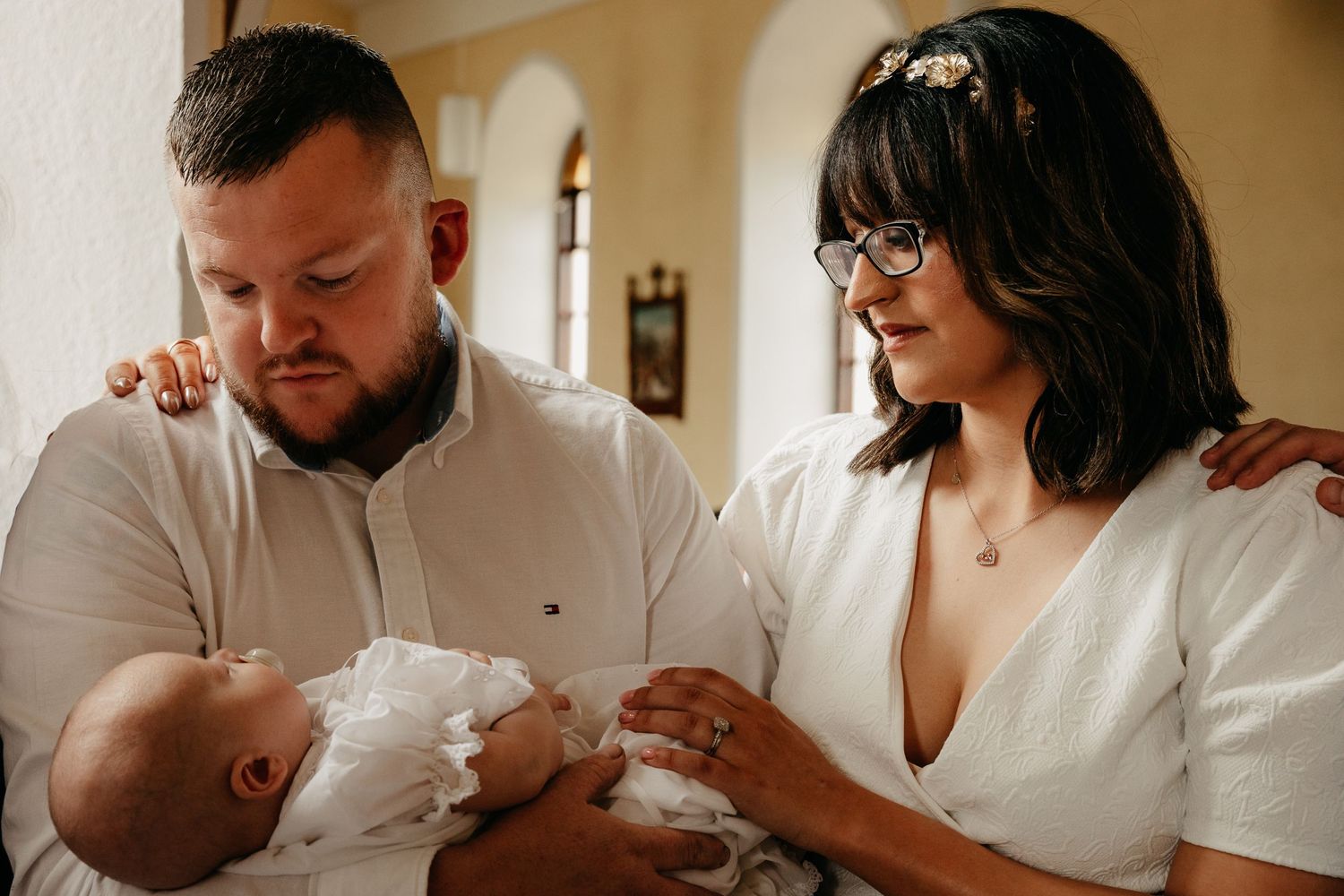 Parents looking down at son during baptism