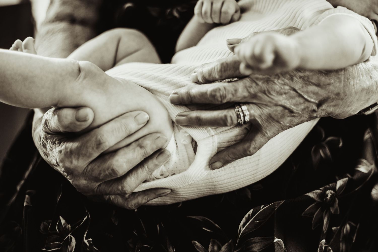 Greatgrandmother's hands holding baby