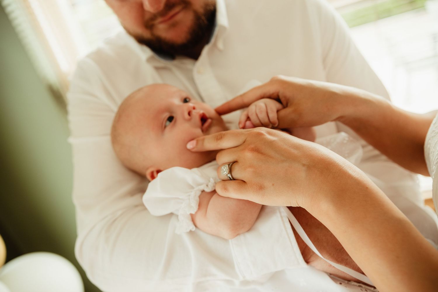 Baby boy held by father. Mother pinching cheeks