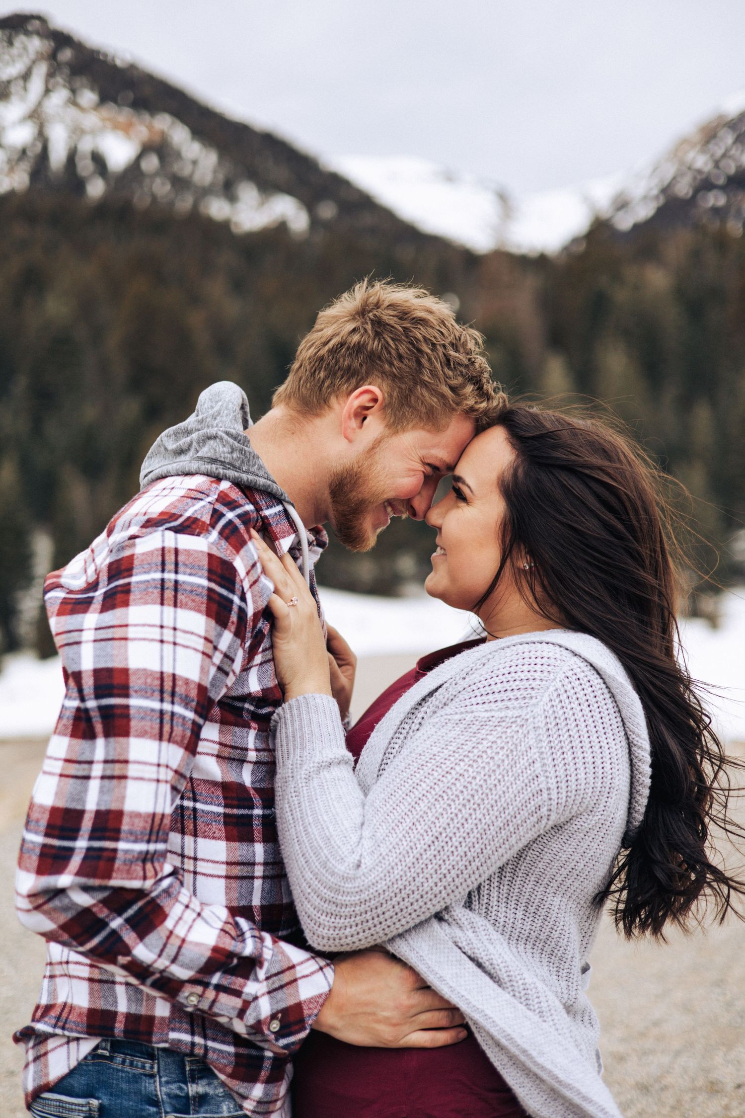 A couple shares an intimate moment in a winter mountain setting.