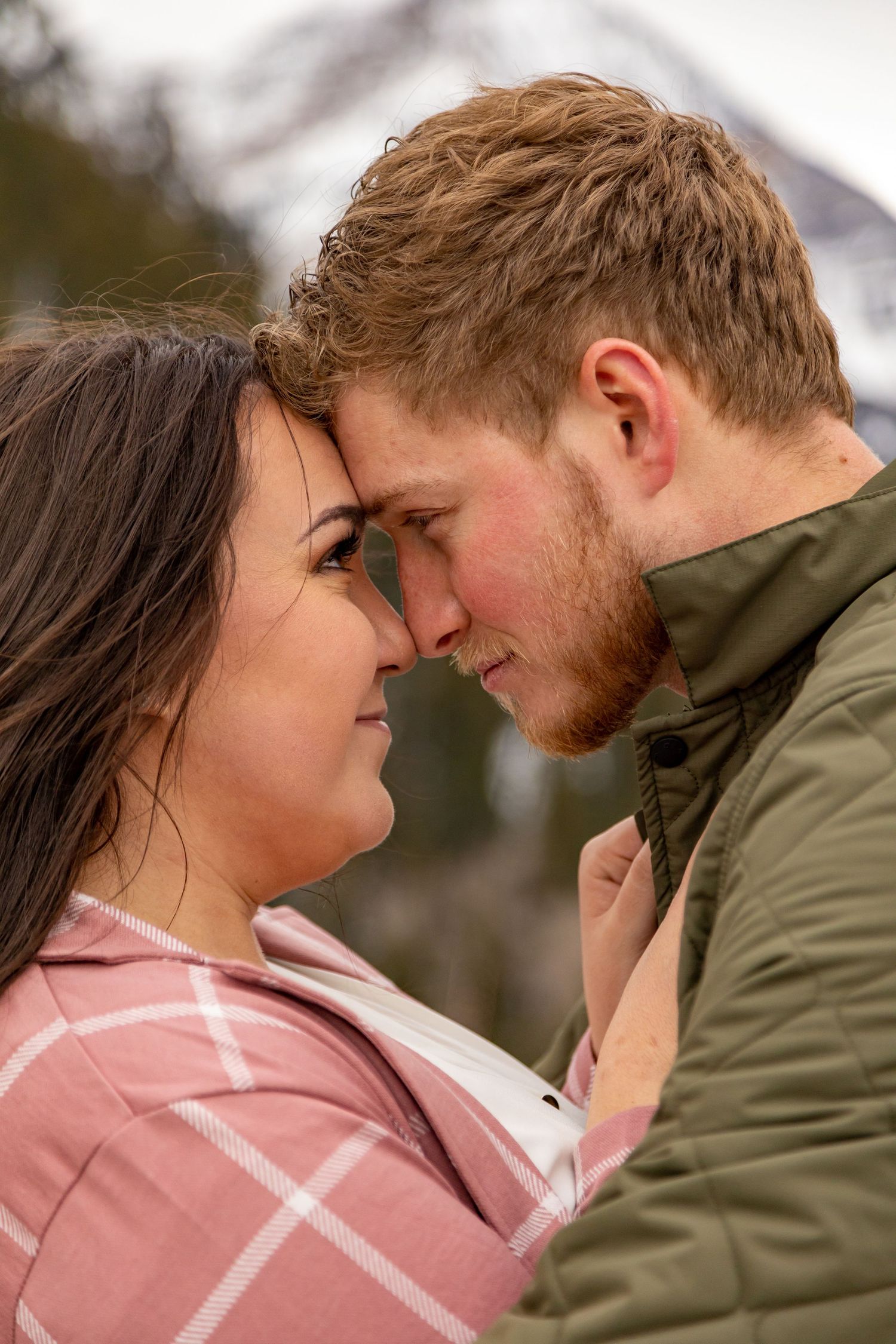An intimate moment shared between a couple against a mountainous winter backdrop.