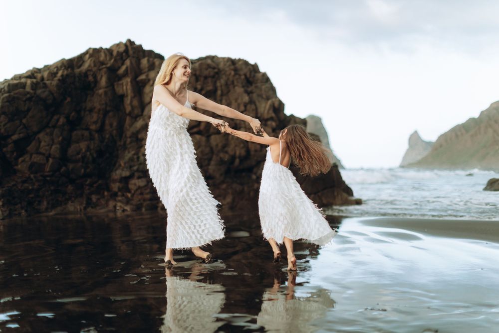 Family enjoying quality time together on a scenic coastal beach with rocky cliffs.