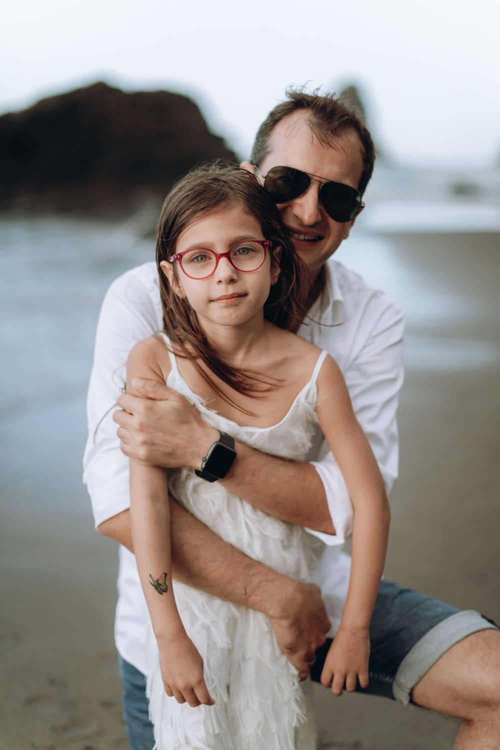 Tender embrace between parent and child on a misty beach.