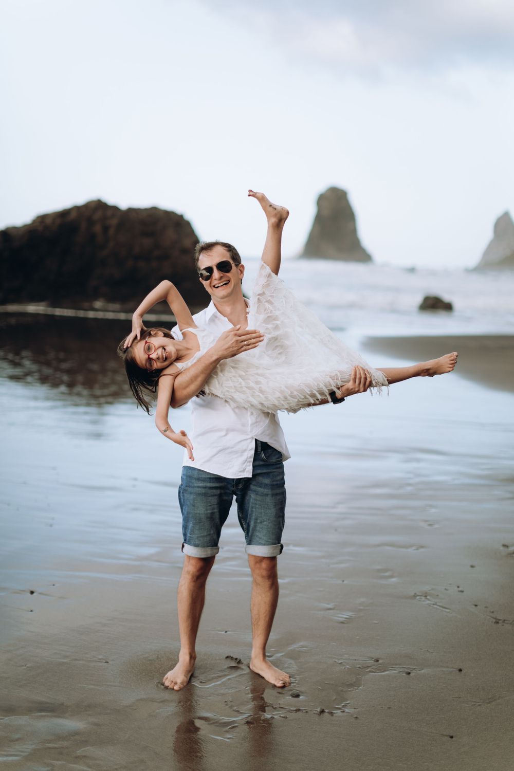 Joyful lift and spin moment between two people on a sandy beach.