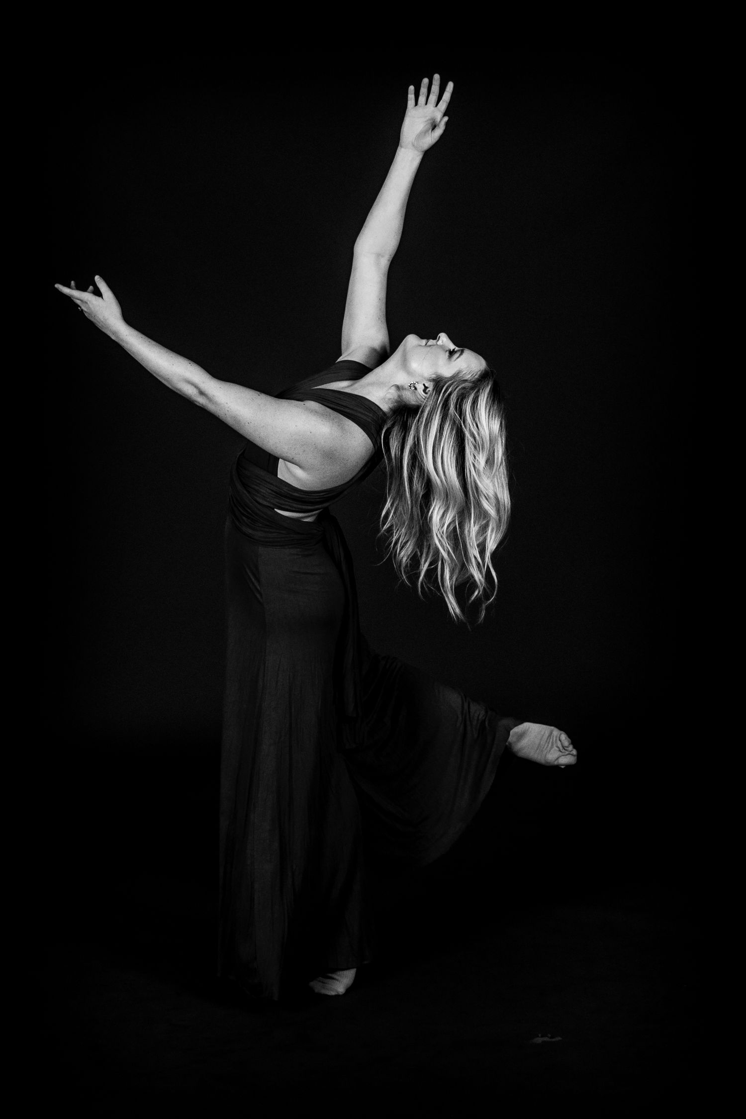 Dramatic black and white photo of dancer in flowing movement against dark background.