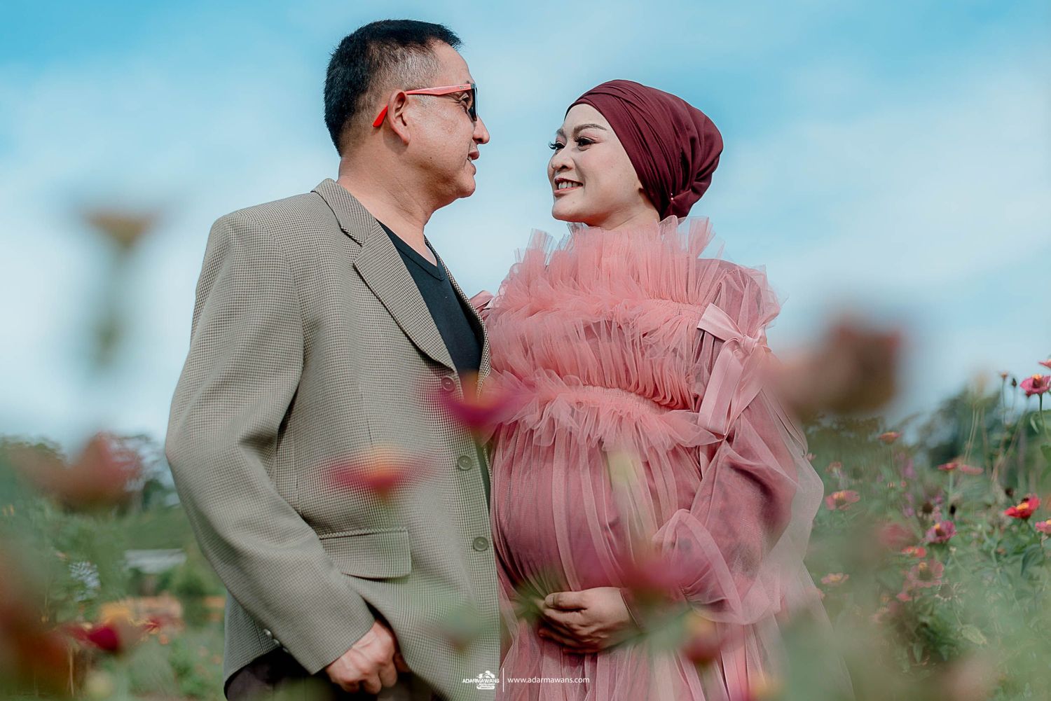 Romantic couple posing in flower field during sunset photoshoot.