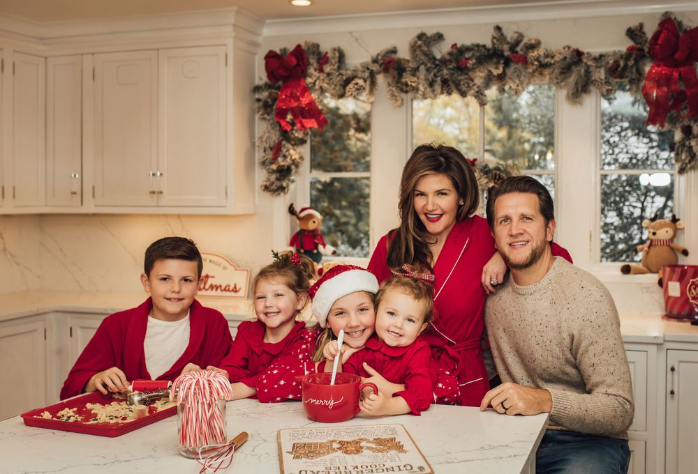 Family gathered in festive kitchen with Christmas decorations and holiday treats.