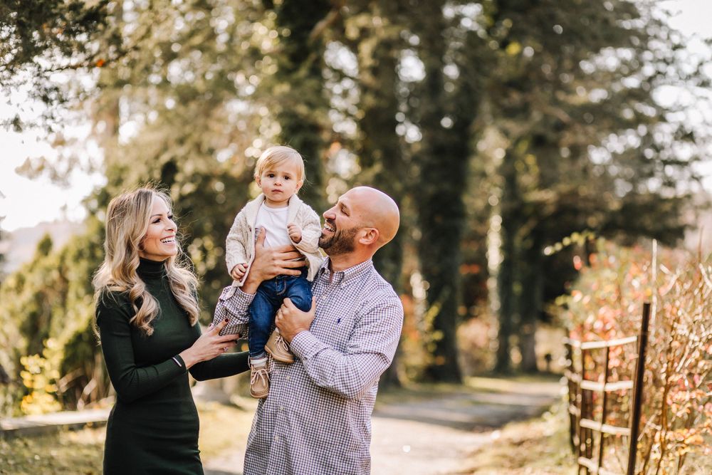Young family enjoying a tender moment together on an autumn path surrounded by trees.