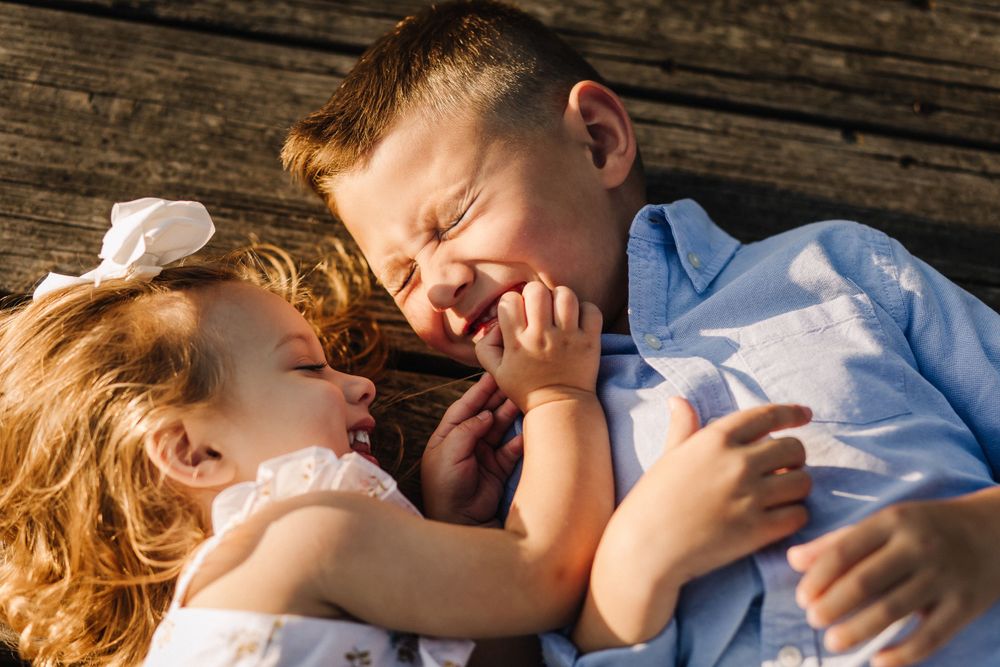 A playful moment captured between parent and child lying on wooden deck.