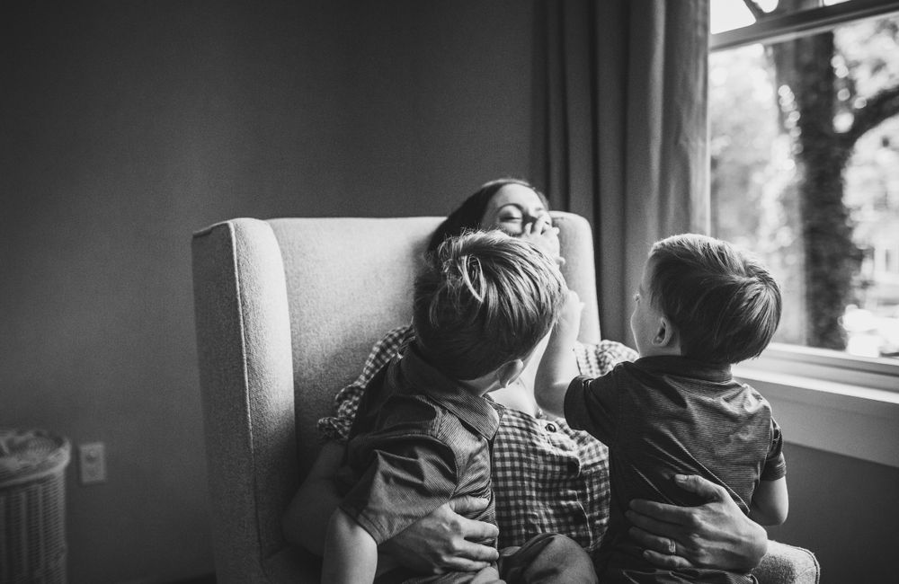 Two children relaxing together in a cozy armchair by the window.