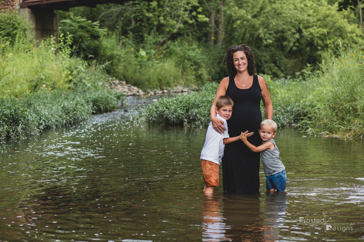 Maternity session with expectant mom and two brothers hugging moms belly.