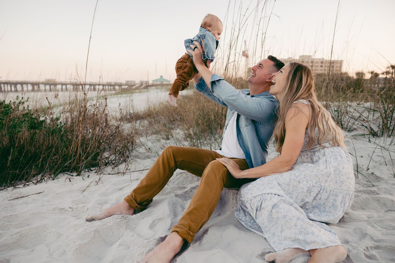 Playful couple poses together on white sand dunes during golden hour.