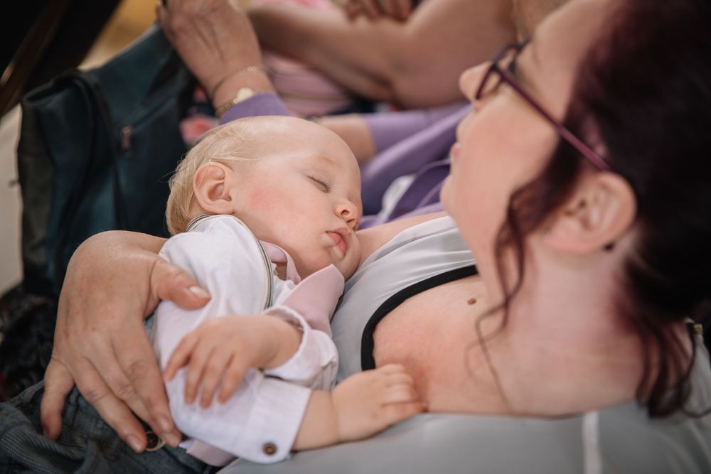 A sleeping baby in white clothing rests peacefully during a tender moment.