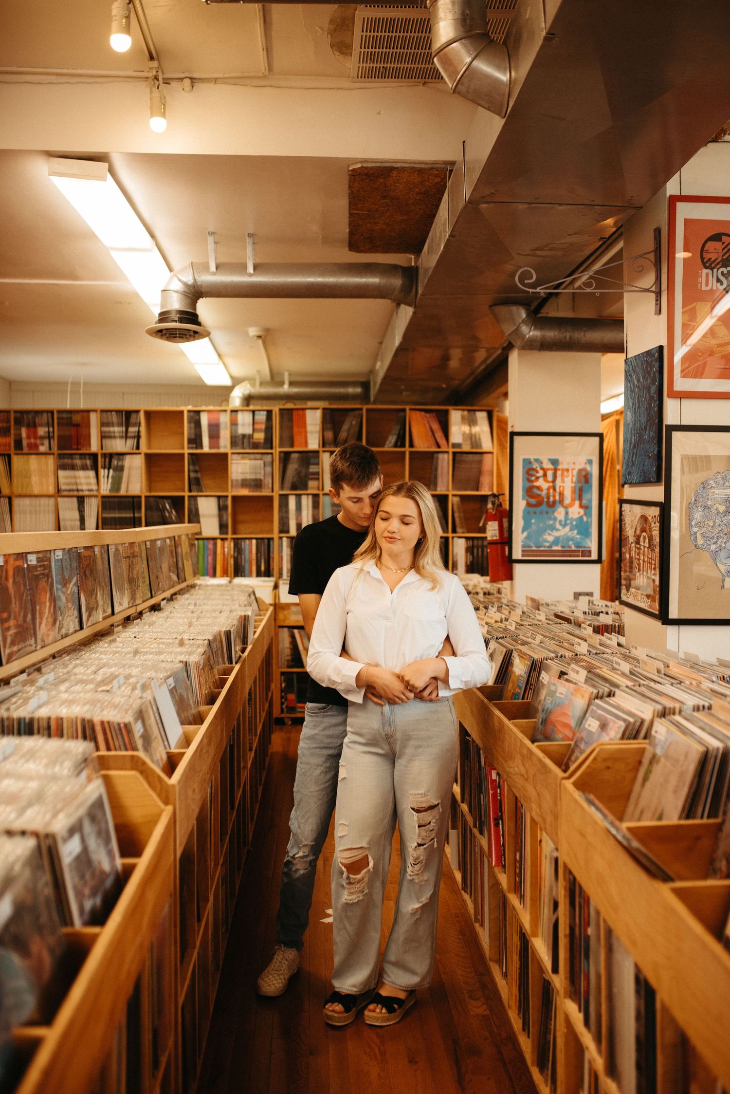 A couple standing close together while browsing vinyl records in a music store aisle.