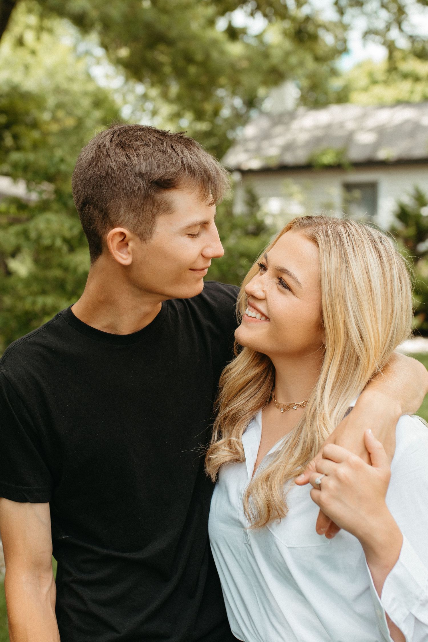 Young couple in casual wear sharing tender moment together in outdoor garden setting.